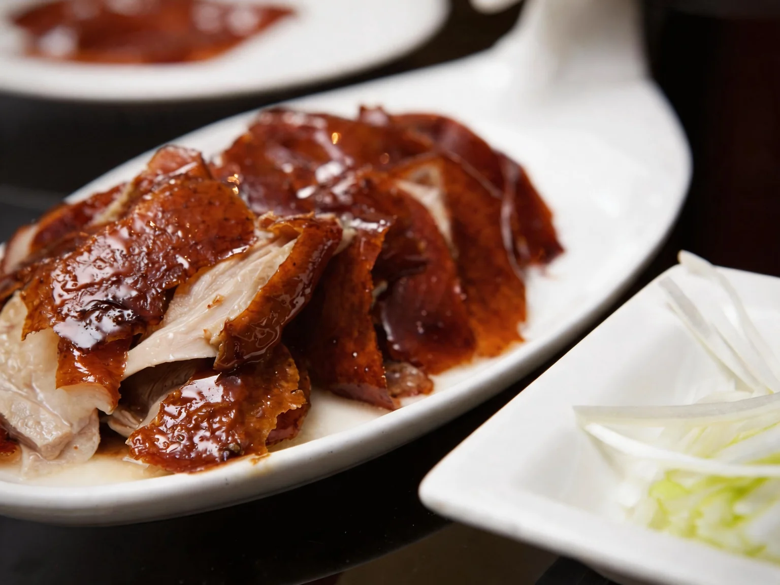 Lacquered duck. Sliced, on a white plate.